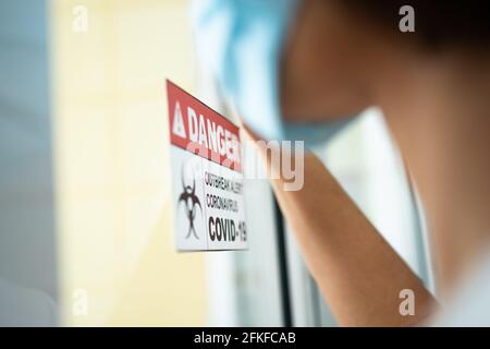 Eine Frau, die vor dem Quarantäneraum steht und eine Hand auf den Spiegel legt, während sie auf die Untersuchungsergebnisse wartet, hat eine Menge Angst. Konz Stockfoto