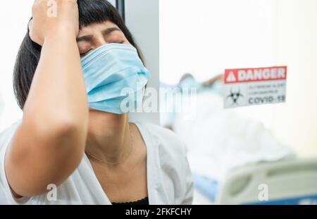 Eine Frau, die vor dem Quarantäneraum steht und Ihren Kopf mit ihren Händen hält, während sie auf die Untersuchungsergebnisse wartet, hat Angst. Konzept Stockfoto