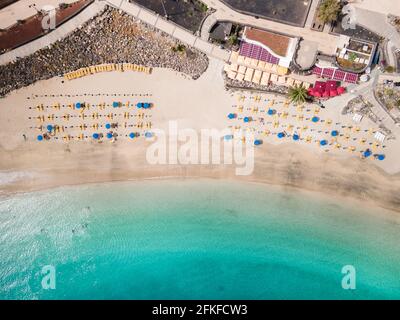 Weißer Sandstrand mit Menschen, Sonnenschirmen und Sonnenliegen aus der Vogelperspektive Stockfoto