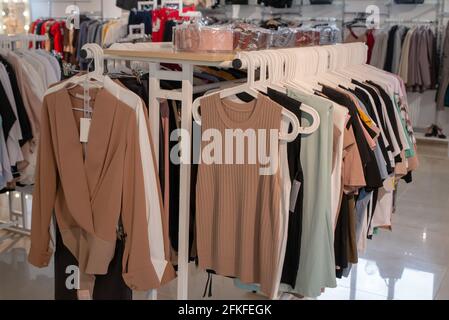 Stilvolle Kollektion von Damenbekleidung, die an Kleiderbügeln im Showroom hängt. Copspace Stockfoto