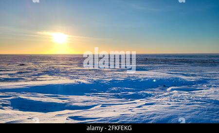 Sonnenaufgang über den Hügeln in der arktischen Tundra im Nordwesten Gebiete über einer schneebedeckten Landschaft Stockfoto