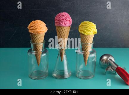Orange Rosa und Gelbe Kugeln Eis auf einem Tisch Mit Blaugrün Stockfoto