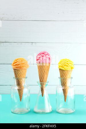 Orange Rosa und Gelbe Kugeln Eis auf einem Tisch Mit Blaugrün Stockfoto