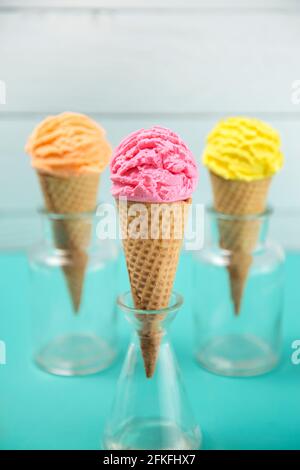 Orange Rosa und Gelbe Kugeln Eis auf einem Tisch Mit Blaugrün Stockfoto