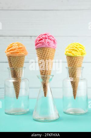 Orange Rosa und Gelbe Kugeln Eis auf einem Tisch Mit Blaugrün Stockfoto