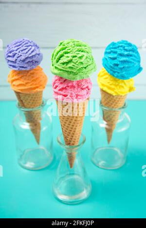 Rainbow Ice Cream schaufeln in Waffelkonen auf einem Teal Tabelle Stockfoto