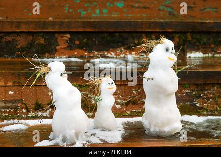 Winter-Frühling Geschichte der Schneemannfamilie: Schneemann-Vater, Schneemann-Mutter, Schneemann-Kind an der Schwelle eines Dorfhauses Stockfoto