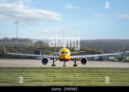 DHL Boeing 737 Düsenflugzeug auf Start- und Landebahn bereit Vom geschäftigen internationalen Verteilungszentrum werden gelb und rot geparkt Stockfoto