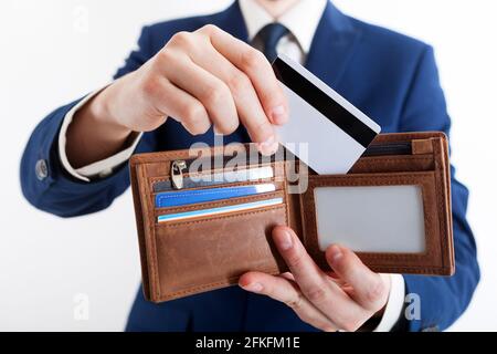 Elegant gekleideter Geschäftsmann, der eine Kreditkarte in die Tasche steckte. Mann in schwarzem Anzug, weißem Hemd und Krawatte. Leere Karte. Geschäftsmann steckt in seine Tasche Stockfoto