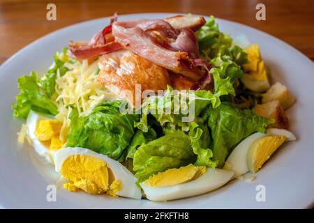 „nicht-traditioneller“ Caesar Salat (Blattgemüse, hartgekochtes Ei, Käse, goldener Bauch, Huhn, Croutons). Stockfoto