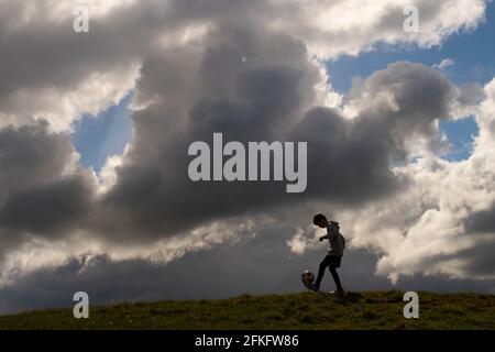 Langshaw Scottish Borders, Großbritannien. Mai 2021. UK UK Weather EIN kleiner Junge praktiziert seine Anhalten-Uppies auf Gras in Langshaw an der schottischen Grenze, mit dramatischen dunklen Regenwolken als Hintergrund. Die Wettervorhersage für die Feiertage sieht nicht vielversprechend aus, da ein Großteil des Vereinigten Königreichs die ersten signifikanten Niederschläge seit langem erwartet, willkommen für Gärtner und Landwirte, aber nicht für diejenigen, die das lange Wochenende der Feiertage am 1. Mai genießen möchten. Quelle: phil wilkinson/Alamy Live News Stockfoto