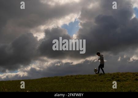 Langshaw Scottish Borders, Großbritannien. Mai 2021. UK UK Weather EIN kleiner Junge praktiziert seine Anhalten-Uppies auf Gras in Langshaw an der schottischen Grenze, mit dramatischen dunklen Regenwolken als Hintergrund. Die Wettervorhersage für die Feiertage sieht nicht vielversprechend aus, da ein Großteil des Vereinigten Königreichs die ersten signifikanten Niederschläge seit langem erwartet, willkommen für Gärtner und Landwirte, aber nicht für diejenigen, die das lange Wochenende der Feiertage am 1. Mai genießen möchten. Quelle: phil wilkinson/Alamy Live News Stockfoto