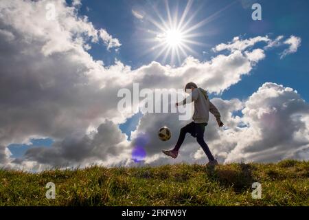 Langshaw Scottish Borders, Großbritannien. Mai 2021. UK UK Weather EIN kleiner Junge praktiziert seine Anhalten-Uppies auf Gras in Langshaw an der schottischen Grenze, mit dramatischen dunklen Regenwolken als Hintergrund. Die Wettervorhersage für die Feiertage sieht nicht vielversprechend aus, da ein Großteil des Vereinigten Königreichs die ersten signifikanten Niederschläge seit langem erwartet, willkommen für Gärtner und Landwirte, aber nicht für diejenigen, die das lange Wochenende der Feiertage am 1. Mai genießen möchten. Quelle: phil wilkinson/Alamy Live News Stockfoto