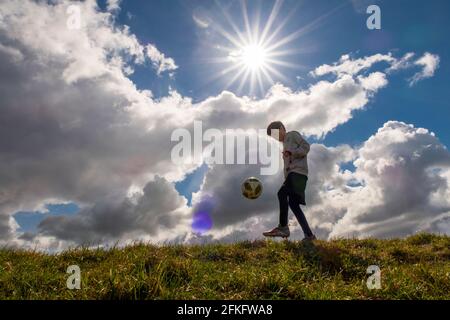 Langshaw Scottish Borders, Großbritannien. Mai 2021. UK UK Weather EIN kleiner Junge praktiziert seine Anhalten-Uppies auf Gras in Langshaw an der schottischen Grenze, mit dramatischen dunklen Regenwolken als Hintergrund. Die Wettervorhersage für die Feiertage sieht nicht vielversprechend aus, da ein Großteil des Vereinigten Königreichs die ersten signifikanten Niederschläge seit langem erwartet, willkommen für Gärtner und Landwirte, aber nicht für diejenigen, die das lange Wochenende der Feiertage am 1. Mai genießen möchten. Quelle: phil wilkinson/Alamy Live News Stockfoto