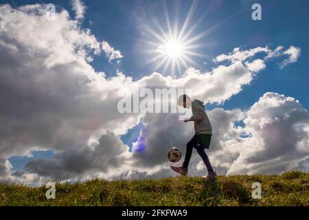 Langshaw Scottish Borders, Großbritannien. Mai 2021. UK UK Weather EIN kleiner Junge praktiziert seine Anhalten-Uppies auf Gras in Langshaw an der schottischen Grenze, mit dramatischen dunklen Regenwolken als Hintergrund. Die Wettervorhersage für die Feiertage sieht nicht vielversprechend aus, da ein Großteil des Vereinigten Königreichs die ersten signifikanten Niederschläge seit langem erwartet, willkommen für Gärtner und Landwirte, aber nicht für diejenigen, die das lange Wochenende der Feiertage am 1. Mai genießen möchten. Quelle: phil wilkinson/Alamy Live News Stockfoto