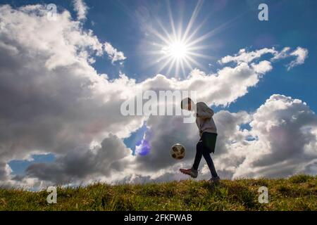 Langshaw Scottish Borders, Großbritannien. Mai 2021. UK UK Weather EIN kleiner Junge praktiziert seine Anhalten-Uppies auf Gras in Langshaw an der schottischen Grenze, mit dramatischen dunklen Regenwolken als Hintergrund. Die Wettervorhersage für die Feiertage sieht nicht vielversprechend aus, da ein Großteil des Vereinigten Königreichs die ersten signifikanten Niederschläge seit langem erwartet, willkommen für Gärtner und Landwirte, aber nicht für diejenigen, die das lange Wochenende der Feiertage am 1. Mai genießen möchten. Quelle: phil wilkinson/Alamy Live News Stockfoto