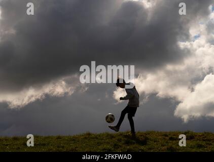 Langshaw Scottish Borders, Großbritannien. Mai 2021. UK UK Weather EIN kleiner Junge praktiziert seine Anhalten-Uppies auf Gras in Langshaw an der schottischen Grenze, mit dramatischen dunklen Regenwolken als Hintergrund. Die Wettervorhersage für die Feiertage sieht nicht vielversprechend aus, da ein Großteil des Vereinigten Königreichs die ersten signifikanten Niederschläge seit langem erwartet, willkommen für Gärtner und Landwirte, aber nicht für diejenigen, die das lange Wochenende der Feiertage am 1. Mai genießen möchten. Quelle: phil wilkinson/Alamy Live News Stockfoto