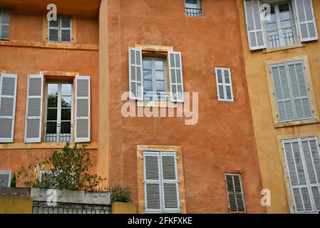 Traditionelle Hausfassade im Provençal-Stil mit ockerfarbener Stuckwand und hölzernen Fensterläden in Aix-en-Provence Marseille, Frankreich. Stockfoto