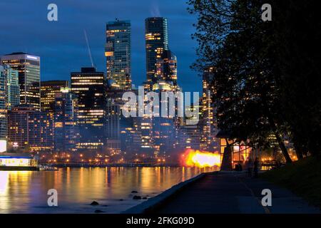 Vancouver Nine O'Clock Gun feuert während der blauen Stunde im Dunkeln mit Stadtbild im Hintergrund, Stanley Park, Vancouver, BC, Kanada. Stockfoto