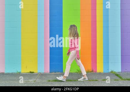 Attraktive ältere Frau, die im Freien gegen eine bunt gestreifte Wand läuft Stockfoto