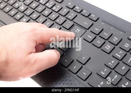Der Finger drückt die Eingabetaste auf einer kabellosen schwarzen Tastatur des PCs. Stockfoto