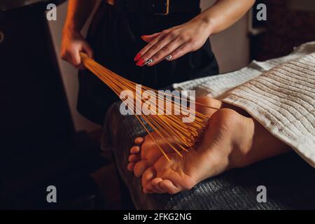 Massage der weiblichen Füße mit Bambusstäbchen Stockfoto