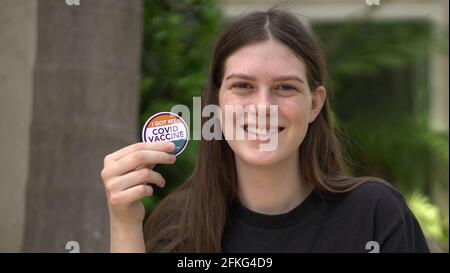 Ein junges Teenager-Mädchen (16) zeigt stolz ihren Aufkleber „Ich habe meinen Covid-Impfstoff“, nachdem sie sich geimpft hat. Stockfoto