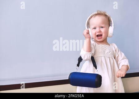 Mädchen hört Musik singt und tanzt in Kopfhörern mit einem Musiklautsprecher in ihren Händen. Speicherplatz kopieren. Stockfoto