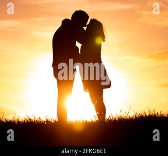 Silhouette eines Paares bei Sonnenuntergang. Schwanger und glücklich, im Freien in der Natur. Stockfoto