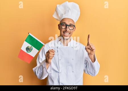 Glatze Mann mit Bart tragen professionelle Koch Schürze hält mexiko Flagge lächeln mit einer Idee oder Frage Zeigefinger mit glücklichem Gesicht, Nummer eins Stockfoto