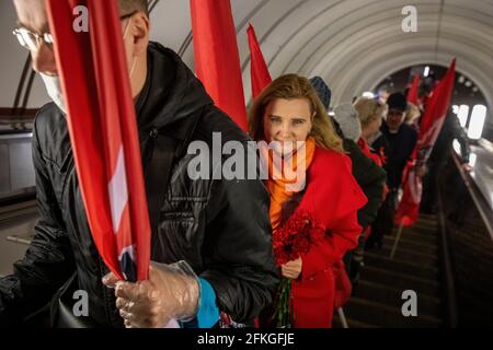 Moskau, Russland. 1. Mai 2021 Anhänger der Linkskront-Bewegung steigen auf die Rolltreppe der U-Bahn-Station Teatralnaja, um am marsch der Kommunisten im Zentrum von Moskau teilzunehmen, der der Feier des 1. Mai (Tag der Arbeit) in Russland gewidmet ist Stockfoto