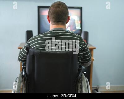 Behinderter Kerl, der sich zu Hause während des Lockdown einen Film am Computer ansieht Zeit, Medizintechnik Stockfoto