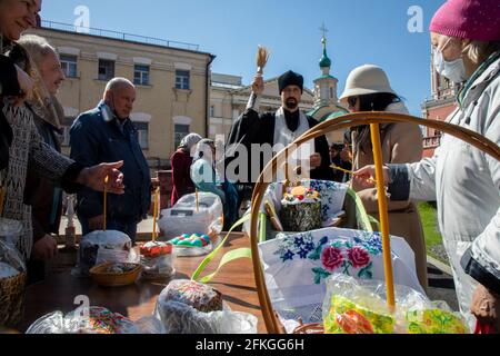 Moskau, Russland. 1. Mai 2021 ein orthodoxer Priester segnet am Vorabend des orthodoxen Osterfestes im Kloster Wysokopetrowski in Moskau, Russland, Kuchen und Eier. Es ist das männliche Stauropegionenkloster der russisch-orthodoxen Kirche in Moskau; im Stadtzentrum an den Abfahrten zum Kreml auf der Petrovka-Straße gelegen Stockfoto