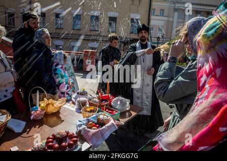 Moskau, Russland. 1. Mai 2021 ein orthodoxer Priester segnet am Vorabend des orthodoxen Osterfestes im Kloster Wysokopetrowski in Moskau, Russland, Kuchen und Eier. Es ist das männliche Stauropegionenkloster der russisch-orthodoxen Kirche in Moskau; im Stadtzentrum an den Abfahrten zum Kreml auf der Petrovka-Straße gelegen Stockfoto