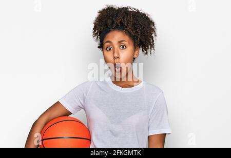Junge afroamerikanische Mädchen spielen Baseballspiele mit Schläger und Ball erschrocken und erstaunt mit offenem Mund für Überraschung, Unglauben Gesicht Stockfoto