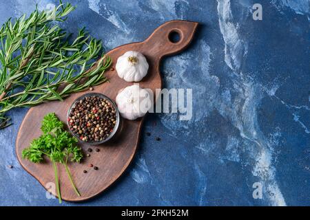 Schale mit Pfefferkörnern und Kräutern auf farbigem Hintergrund Stockfoto