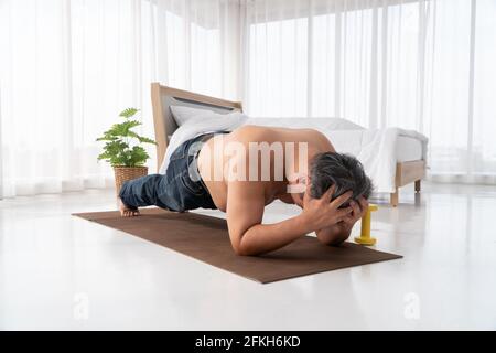 Fat asiatische Männer versuchen, Planken mit Entschlossenheit zu machen und versuchen hart, Gewicht zu verlieren. Beim Betreten vor dem Ausgehen zur Arbeit. Konzept des Workouts Stockfoto