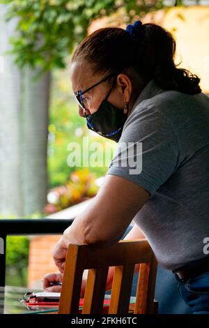 Medellin, Kolumbien - März 28 2021: Ältere lateinische Frau arbeitet als Kellnerin in einem Restaurant, das die Tische serviert Stockfoto