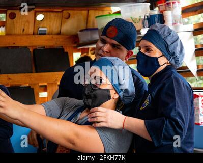 Medellin, Kolumbien - März 28 2021: Lateinamerikanische Frauen und hispanischer Mann in blauer Uniform und Stoffhut bei einem Selfie mit seinem Handy Stockfoto