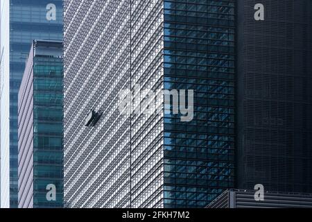 Fensterputzer in einer Gondel (Building Maintenance Unit BMU) auf Wolkenkratzern in Otemachi, Tokio, Japan Stockfoto