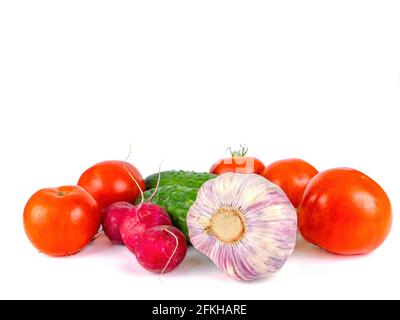 Knoblauchkopf mit Gurken und Tomaten auf einem weißen Teller. Kopf des Knoblauchs. Rettichgemüse. Gemüse, Gurken und Tomaten. Roter Rettich. Vegetar Stockfoto