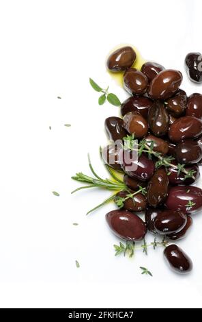 Schwarze Oliven und aromatische Kräuter auf weißem Hintergrund. Direkt darüber. Stockfoto