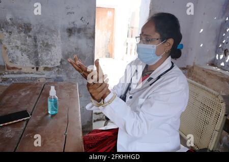 Eine indische weibliche medizinische Fachkraft trägt medizinische Gesichtsmaske und Laborkittel mit einem Stethoskop um den Hals, das die Hände desinfiziert Während Covid-19 Stockfoto