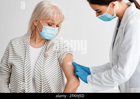 Reifer Patient, Der Gegen Covid-19 Geimpft Wird, Arzt, Der Gips Anwendet Stockfoto