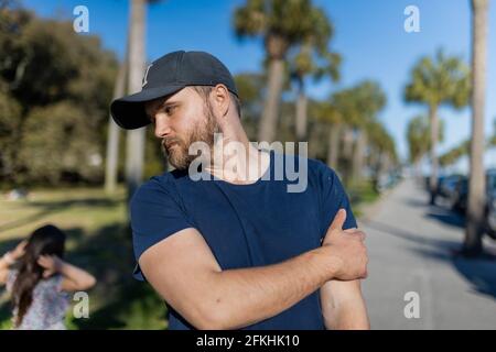 Bärtiger Mann, der mit Palmen und blauem Himmel steht Hintergrund Stockfoto