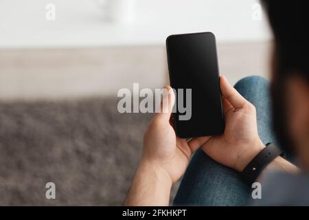 Menschen- und Technologiekonzept. Über die Schulter Ansicht von Kerl mit Smartphone mit leerem Bildschirm für Mockup Stockfoto