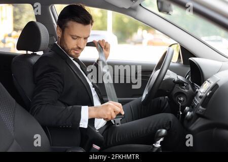 Ein Geschäftsmann in Anzug schnallte den Sicherheitsgurt in sein Auto Stockfoto