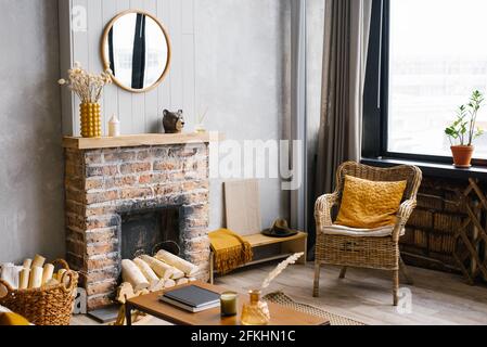 Gemütliches Interieur des Wohnzimmers Rattan Stuhl und Kamin. Rustikales Design des Hauses für einen warmen Innenraum eines Alpenurlaumes. Moderne Einrichtung o Stockfoto