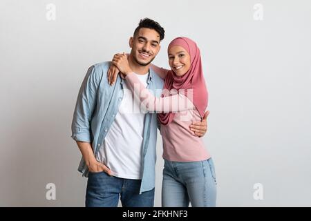 Junge Islamische Familie. Glückliche Muslimische Ehegatten Umarmen Und Lächeln Camera An Stockfoto