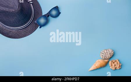 Flache Muschellage auf blauem Hintergrund. Muscheln und Hut auf pastellfarbenem Hintergrund. Urlaubskonzept Stockfoto